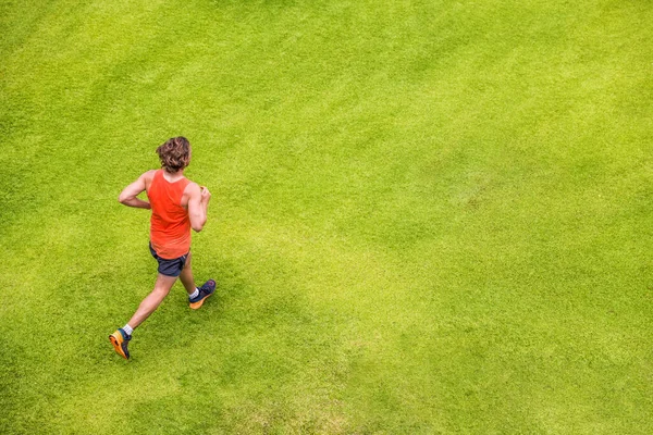 Runner man running on summer grass park jogging healthy lifestyle. People working out cardio top view. Copy space on green texture background — Stok fotoğraf