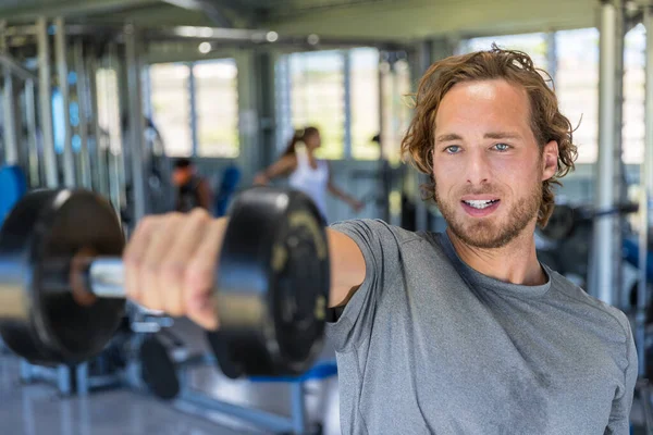 Gym man fitnessträning armmuskler lyfta fria vikter. Idrottare gör hantelhöjare fram för axelträning — Stockfoto