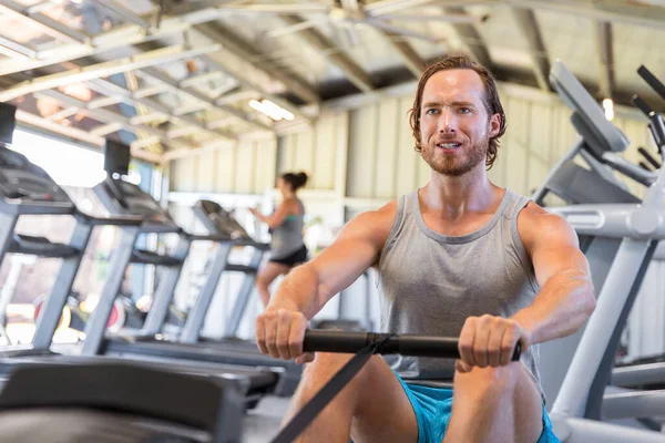 Homem atleta formação cardio na máquina de remo no ginásio fitness — Fotografia de Stock