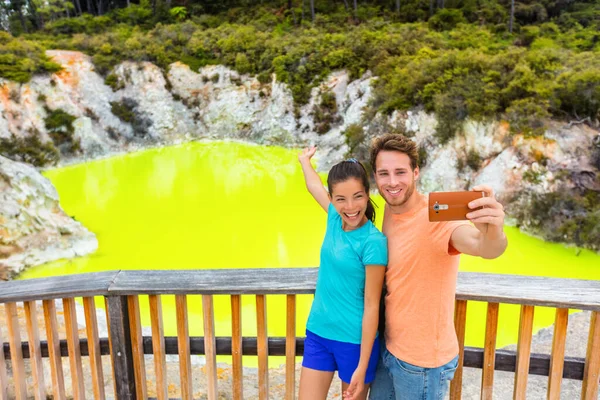 Nowa Zelandia atrakcją turystyczną para turystów biorąc selfie cel podróży, Waiotapu. Aktywny staw zieleni geotermalnej, Rotorua, wyspa północna, Wai-O-Tapu, Nowa Zelandia. — Zdjęcie stockowe