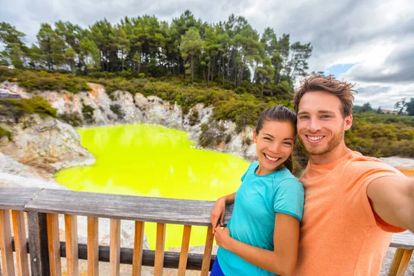 New Zealand tourist attraction couple tourists taking selfie travel destination, Waiotapu. Active geothermal green pond, Rotorua, north island. — Foto de Stock