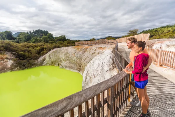 New Zealand travel tourists looking at green pond. Tourist couple enjoying famous attraction on North Island, geothermal pools at Waiotapu, Rotorua. — Foto de Stock