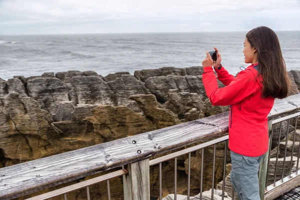 Nowa Zelandia podróżuje turystką robiąc zdjęcia smartfonom z aplikacją telefoniczną w Punakaiki Pancake Rocks. Kobieta w Parku Narodowym Paparoa, Zachodnie Wybrzeże, Wyspa Południowa, Nowa Zelandia — Zdjęcie stockowe