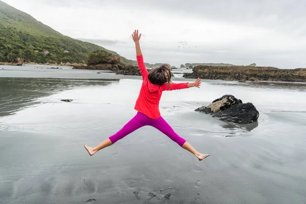 Bekymmersfri glad flicka hoppa av kul på stranden - Kvinna njuter av friluftsliv gör star jump på semester resor. — Stockfoto