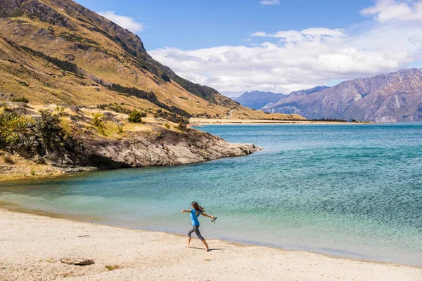 Nieuw-Zeeland reizen gelukkige toeristische vrouw lopen van vreugde en vrijheid aan het strand oever van het meer Hawea natuurlandschap. Nabij Wanaka, regio Otago — Stockfoto