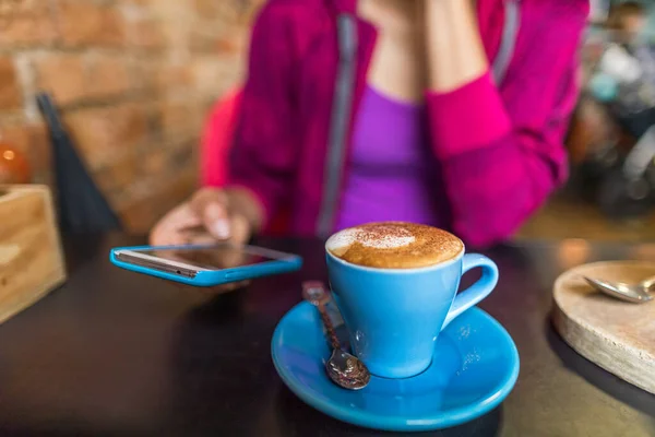 Cafe vrouw het drinken van cappuccino koffiekopje met behulp van mobiele telefoon app. Stedelijke levensstijl jongeren verslaafd aan sociale media online. — Stockfoto