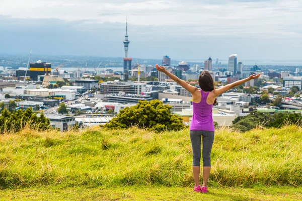 Auckland stad skyline uitzicht vanaf Mount Eden of Sky toren, Nieuw-Zeeland. Gelukkige vrouw met armen omhoog in vrijheid en geluk op de top van Mt Eden urban park beroemde toeristische attractie. — Stockfoto