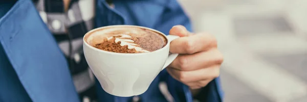 Coffee cup cappuccino woman drinking latte at outdoor cafe. Coffee shop city lifestyle banner panorama closeup of hand holding latte art cup. — Photo