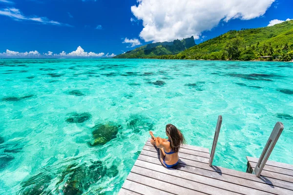 Bora bora luxury travel overwater bungalow resort vacation bikini woman at Tahiti hotel. Tropical exotic destination. Girl relaxing sitting on private balcony under the sun looking at ocean — Stock Photo, Image