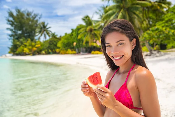 Praia verão estilo de vida menina feliz comer fatia de fruta fresca melancia desfrutando de férias tropicais ao sol. Mulher asiática relaxante bronzeamento em férias exóticas — Fotografia de Stock