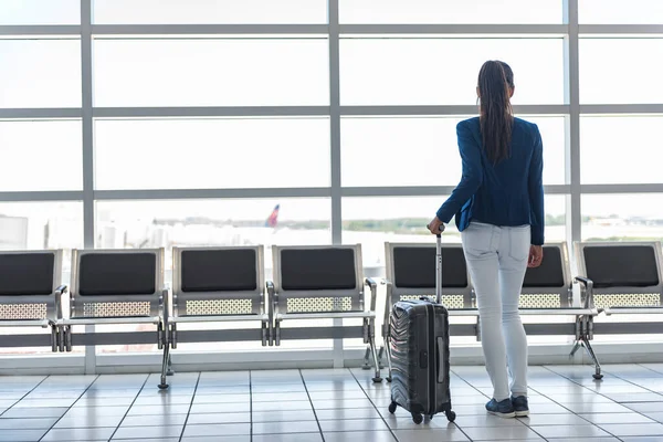 Resor turist väntar på flygplatsen lounge med resväska på asfalt fönster. Oigenkännlig kvinna tittar på loungen tittar på flygplan medan du väntar vid gaten före avgång. Reselivsstil. — Stockfoto