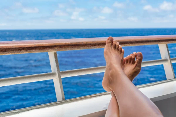 Crucero mujer de viaje de vacaciones relajarse con los pies en la cubierta del barco balcón disfrutando de la vista al mar de destino de vacaciones. Primer plano de las piernas y barandilla del barco. — Foto de Stock
