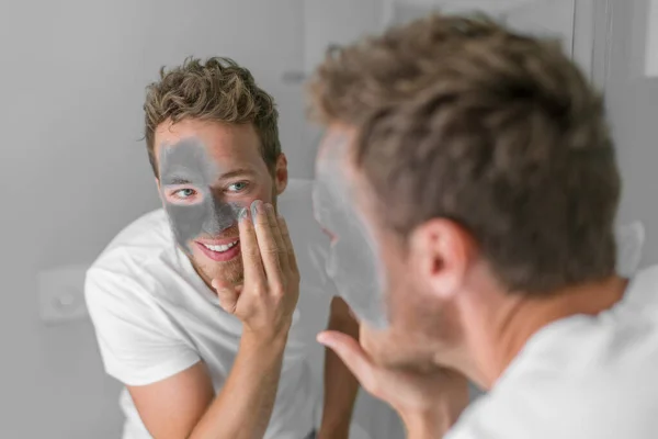 Uomini bellezza caucasico giovane uomo applicando fango argilla maschera disintossicante per affrontare. Trattamento viso con carbone per la cura della pelle maschile — Foto Stock