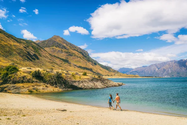 Yeni Zelanda, Hawea Gölü 'nün kıyısında yürüyen Otago bölgesini ziyaret eden turistleri ziyaret ediyor. Wanaka yakınlarındaki plajda mutlu bir adam ve kadın. Serseri genç yürüyüşçüler macera yaşam tarzı — Stok fotoğraf