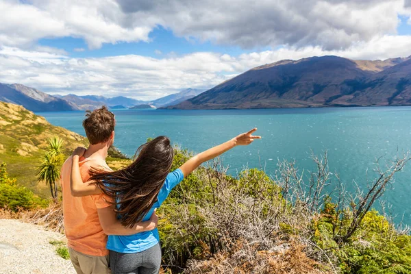 Couple de voyage profitant d'un voyage en voiture wanderlust en Nouvelle-Zélande, femme avec bras levé dans l'excitation à la vue sur le lac en Nouvelle-Zélande. Trampers voyage été destination paysage — Photo