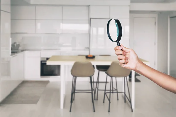 Домашняя проверка - инспектор по увеличительному стеклу смотрит на задний план кухонного дома — стоковое фото