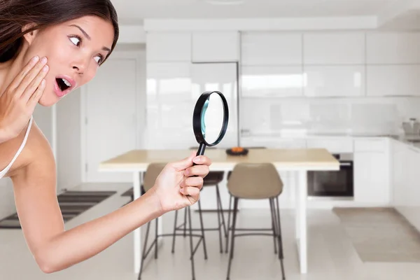 Huiseigenaar vrouw inspecteren keuken met vergrootglas op zoek naar apparaten of winkelen verkoop voor interieur meubels decoratie. Aziatisch meisje verrast bij geheime verrassing huis renovatie — Stockfoto