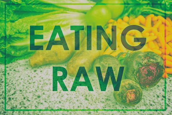 Äta RAW-text skriven över gröna grönsaker bakgrund som reklam för mat diet trend. Vegetariska veganska ingredienser såsom potatis, morötter, sallad, betor som visas på marknaden för jordbrukare — Stockfoto