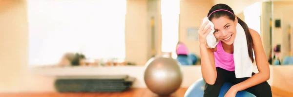 Aziatische fitness meisje training in de sportschool vegen zweet met handdoek post workout blij in de sportschool achtergrond. Panorama gewas met kopieerruimte op gym interieur. Oefening en gezond levend gewichtsverlies concept — Stockfoto