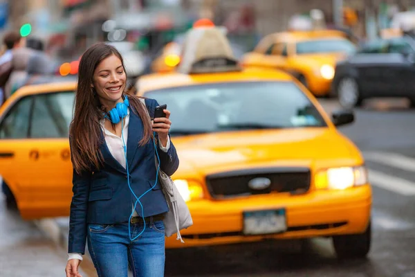 Jeune femme marchant dans la ville de New York en utilisant l'application téléphonique pour une promenade en taxi grêlant avec des écouteurs qui se déplacent du travail. Asiatique fille heureux textos sur smartphone. Urban walk banlieue NYC — Photo