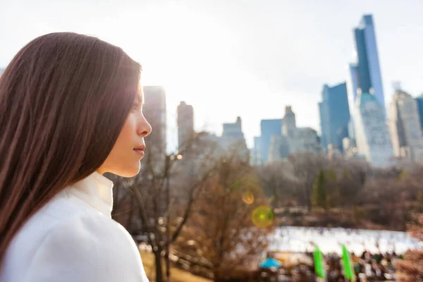 New York City 'li Asyalı kadın kışın Central Park' ta buz pateni pistinin yanında New York 'un siluetinin arka planına bakarak yürüyor. Şehir yaşam tarzı açık havada yaşayan insanlar. — Stok fotoğraf