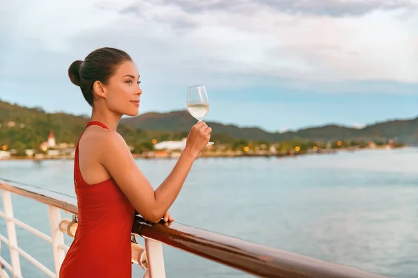 Luxury cruise ship travel elegant Asian woman drinking wine glass drink enjoying watching sunset from boat deck over ocean in summer vacation destination. Cruising sailing away on holiday — Stock Photo, Image