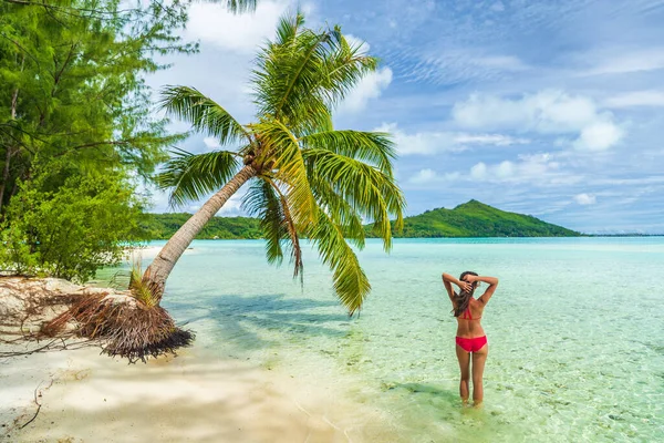 タヒチ島のパラダイス高級ビーチ休暇フランス領ポリネシアの女性は、ターコイズブルーの完璧な水で泳ぐ赤いビキニ水着でリラックスしてください。後ろからのスリムな体の眺め — ストック写真