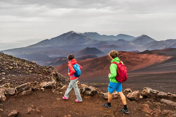 Vulcões havaianos caminhantes pessoas caminhando em montanhas em Haleakala paisagem vulcânica fundo. Dois jovens turistas casal em caminhada ao ar livre. — Fotografia de Stock