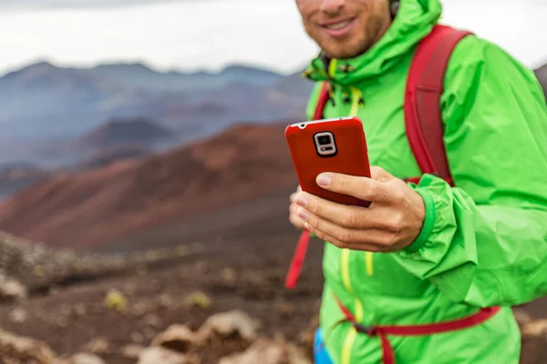 Telefoncu volkan dağında yürüyüş yaparken mesaj atıyor. İnternet 'te akıllı telefonunu kullanarak seyahat eden genç insan. — Stok fotoğraf