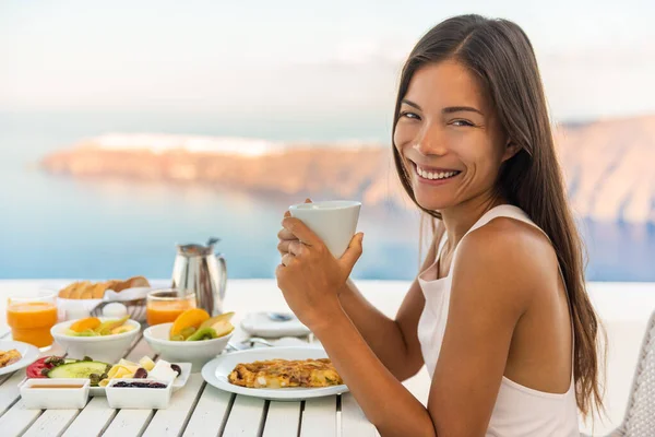 Breakfast woman eating brunch at luxury travel hotel restaurant drinking coffee cup over Mediterranean view from outside balcony. Greek healthy food Santonini vacation. — Stock Photo, Image