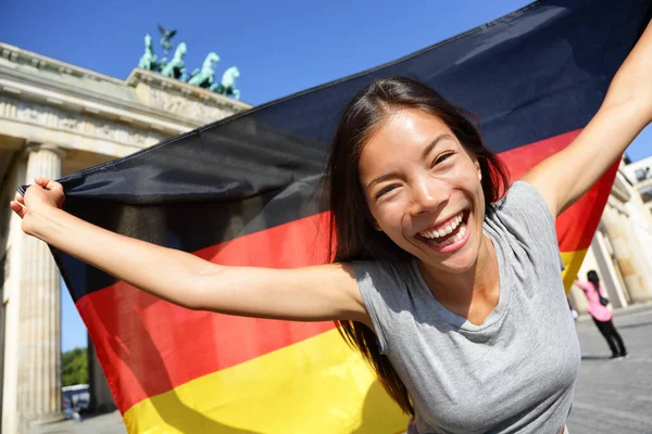 Lycklig kvinna med tysk flagg vid Brandenburger Tor — Stockfoto