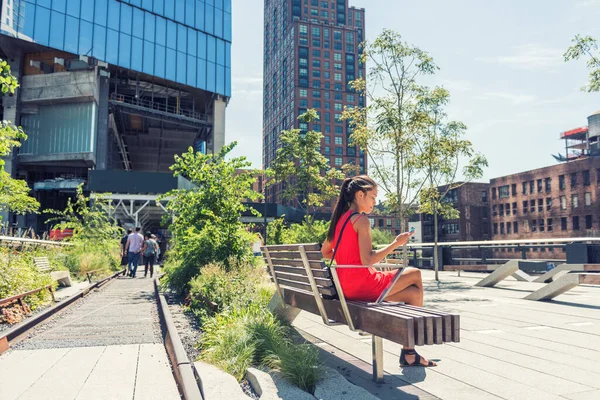Νέα Υόρκη lifestyle γυναίκα στο κινητό τηλέφωνο σε αστικό πάρκο υψηλής γραμμής NYC. Τουριστικά ταξίδια κορίτσι διακοπές κάθεται σε beanch γραπτών μηνυμάτων σε εφαρμογή smartphone επίσκεψη Μανχάταν τουριστικό αξιοθέατο — Φωτογραφία Αρχείου