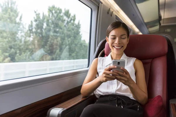 Smiling Asian businesswoman using smartphone social media app while commuting to work in train. Woman sitting in transport enjoying travel — Stock Photo, Image