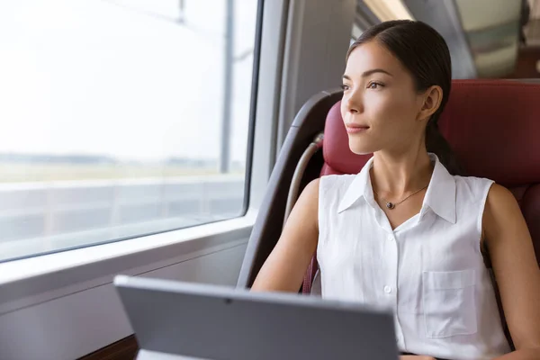 Asian woman traveling using laptop in train. Businesswoman pensive looking out the window while working on computer on travel commute to work — Stock Photo, Image