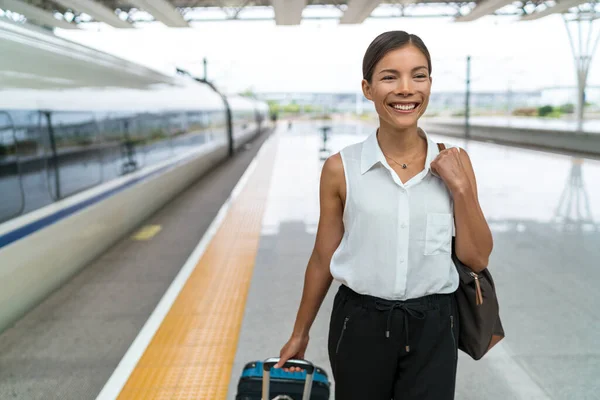 Tren istasyonundaki iş kadını varış noktasına varırken el bagajıyla araçtan ayrıldı. Şehirde işe gidip gelen mutlu Asyalı kadın. — Stok fotoğraf