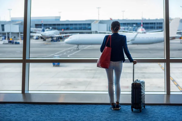 Affärskvinna som reser på flygplatsen. Kvinna tittar genom fönstret på asfalt och flygplan väntar på flyg. Affärsresor — Stockfoto