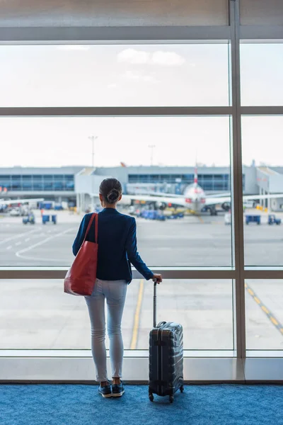 Havaalanı terminalinde uçan kadın silueti bekliyor. İniş pisti ve uçaklara bakan bir iş kadını. İş seyahati kavramı — Stok fotoğraf