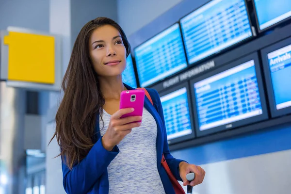 Mujer viajera usando smartphone en el aeropuerto. Joven viajero asiático comprobando la hora de embarque con la aplicación de teléfono móvil en la terminal o estación de tren. Turista de vacaciones — Foto de Stock