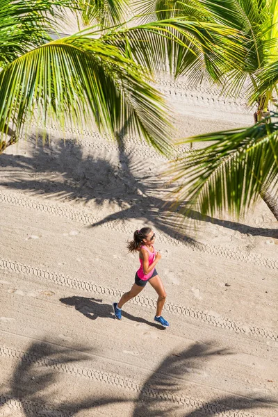 Sano stile di vita attivo sport donna in esecuzione facendo esercizio fisico sulla spiaggia tropicale tra le palme. Vista dall'alto del terreno e dalla sabbia. Concetto di salute e fitness — Foto Stock