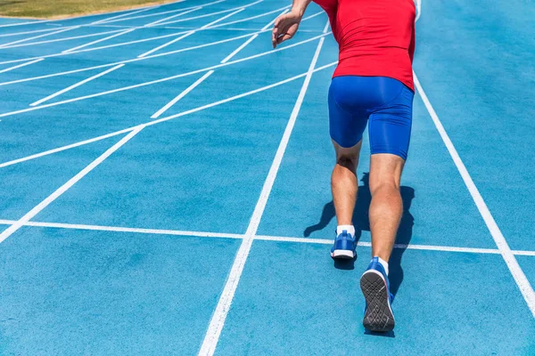 Läuferinnen und Läufer starten am Start der Laufstrecke auf den blauen Laufbahnen im Leichtathletik- und Freiluftstadion. Sprinter. Sport und Fitness Mann Unterkörper, Beine und Laufschuhe sprinten. — Stockfoto