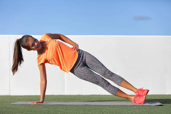 Planche latérale fitness femme entraînement corps noyau planche exercice. Entraînement à la salle de gym extérieure ou jardin à la maison asiatique fille exerçant obliques abdominaux muscles avec planche de pose de yoga. — Photo