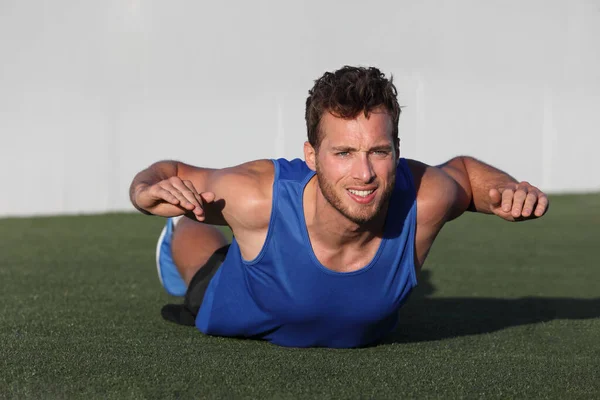 Fitness training terug vet oefening fit man doen superman variatie van lagere lichaamstraining. Sterke atleet die buiten traint in parkgras. Onderlichaam rug lendenspieren versterking oefeningen. — Stockfoto