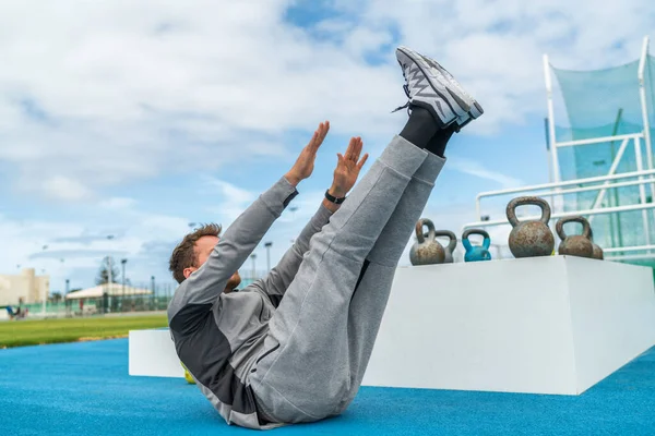 Abs Übung Beinheben Zeh berühren Sit-up Workout Mann Krafttraining im Fitnessstudio Leichtathletikstadion. Sportler trainiert Crunches-Übungen für Bauchmuskeln und Gewichtsverlust. — Stockfoto