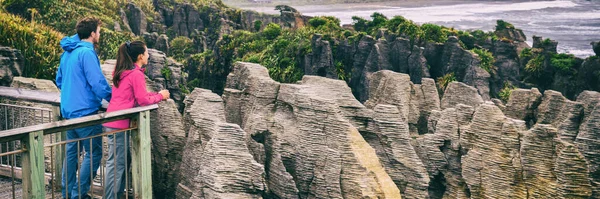 Nueva Zelanda turismo estilo de vida. Punakaiki Pancake Rocks turistas pareja viajan en el Parque Nacional de Paparoa, Costa Oeste, Isla Sur, Nueva Zelanda. Banner panorámico. —  Fotos de Stock