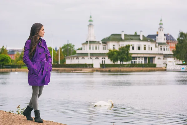 Woman in purple trench coat walking in city park relaxing on weekend. Person enjoying lake view in Copenhagen, Denmark. Spring lifestyle activity, people outside. — Stock Photo, Image