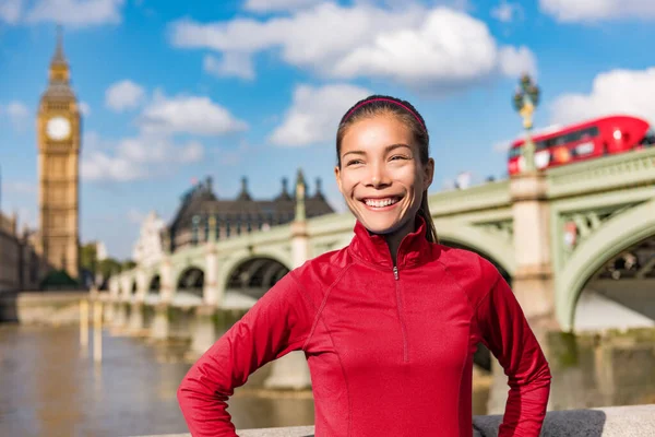 Londyńska kobieta ze stylem życia biegnie koło Big Bena. Biegaczka trening joggingowy w mieście z czerwonym piętrowym autobusem. Fitness girl smiling happy on Westminster Bridge, Londyn, Anglia, Wielka Brytania — Zdjęcie stockowe