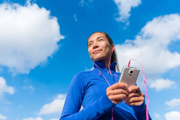 Löpande flicka lyssnar på musik på smarttelefon — Stockfoto