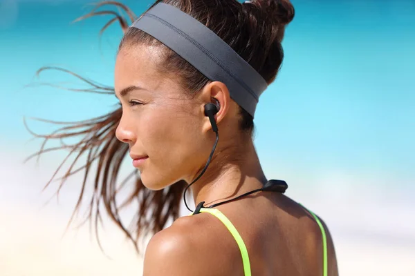 Fitness meisje met sport in-ear draadloze hoofdtelefoon. Aziatische vrouwelijke atleet vrouw loper het dragen van Bluetooth oortelefoons met vleugel tip ontwerp voor sportieve activiteiten. Portret close-up. — Stockfoto