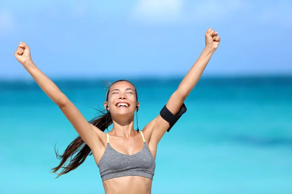 Feliz mujer corriendo ganar - concepto de meta de fitness. Joven corredor asiático sonriendo de felicidad animando con los brazos arriba usando un sujetador deportivo, auriculares y brazalete de teléfono animando el éxito. — Foto de Stock