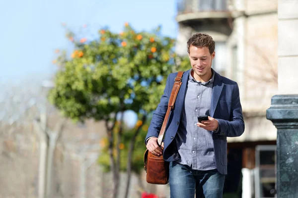 Jovem empresário urbano profissional no smartphone andando na rua usando o aplicativo de telefone celular mensagem SMS sms no smartphone vestindo casaco casual inteligente. Estilo de vida da cidade pessoa comutar andando. — Fotografia de Stock